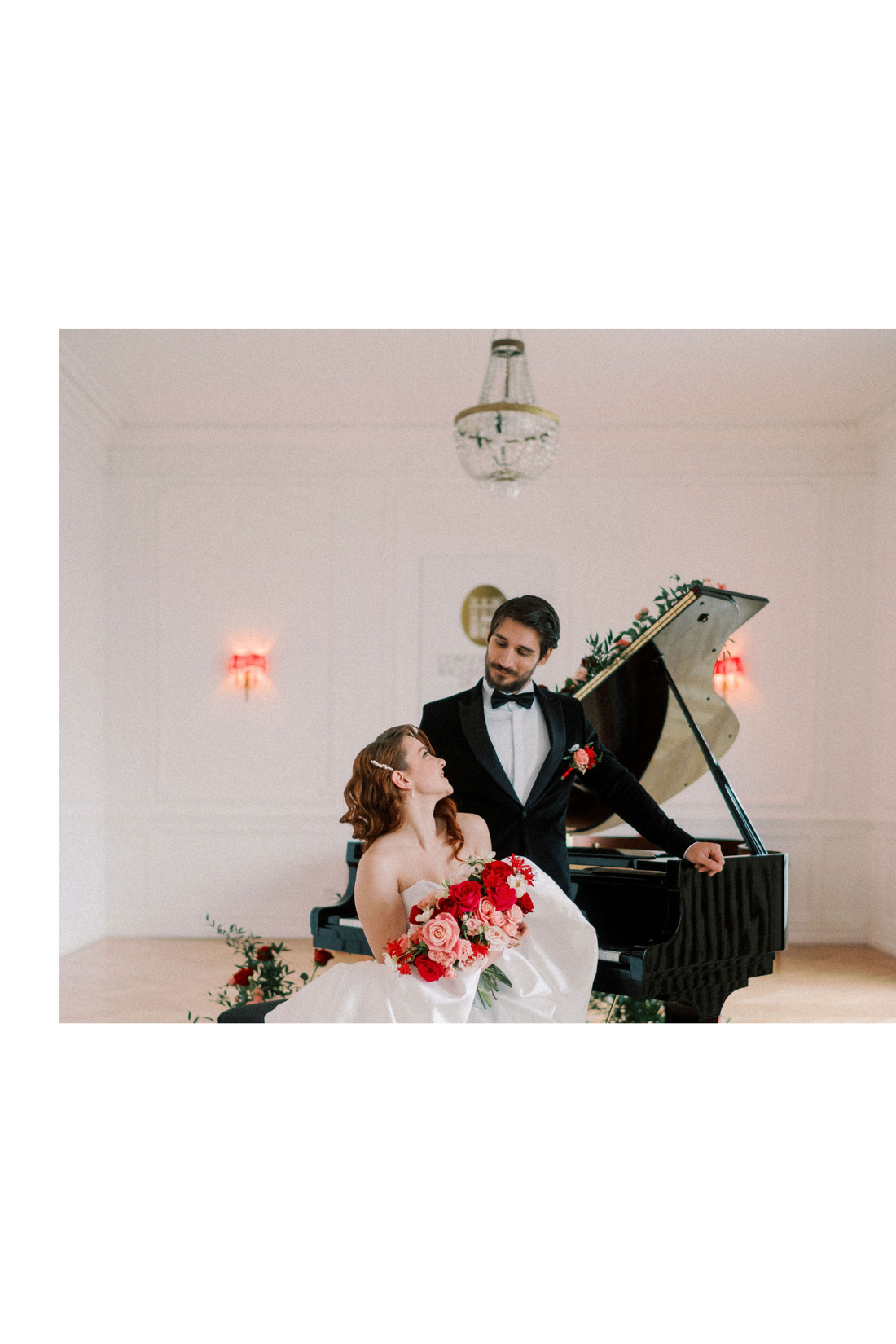 Un couple de mariée avec des fleurs rouges et roses et un peigne de mariée avec des perles et une boutonniére près d'un piano, très élégants
